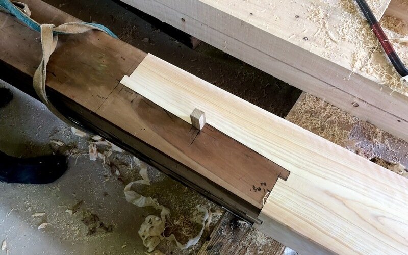 Master carpenter using traditional hand chisels and planes for hand-crafting reclaimed wood